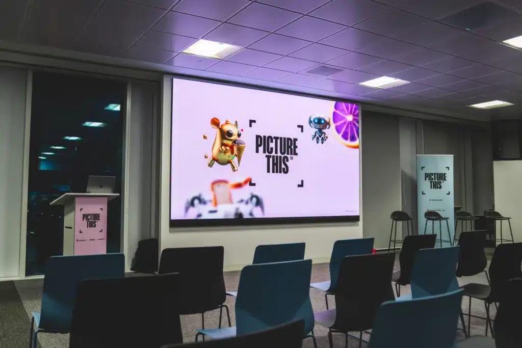 A playful animated character illustration shown on screen at a Picture This event